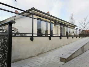 Terrasse extérieure résidentielle avec pergola métallique noire et toiture transparente