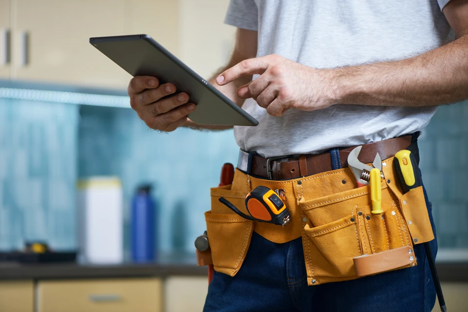 Artisan en tenue de travail consulte une tablette numérique dans une cuisine moderne