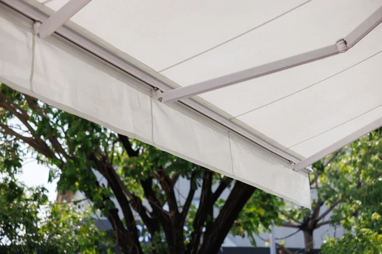Extérieur résidentiel avec store banne rétractable déployé au-dessus d'une terrasse