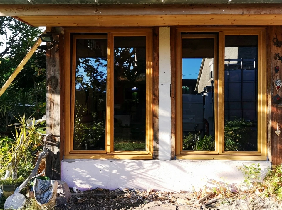 Vue rapprochée d'une fenêtre PVC ou aluminium de qualité supérieure, en cours de pose par les mains gantées d'un artisan menuisier, montrant la précision de l'installation, les joints d'étanchéité et les fixations, en contexte de rénovation extérieure d'une maison. L'image doit transmettre la fiabilité, le professionnalisme et la durabilité du travail réalisé.