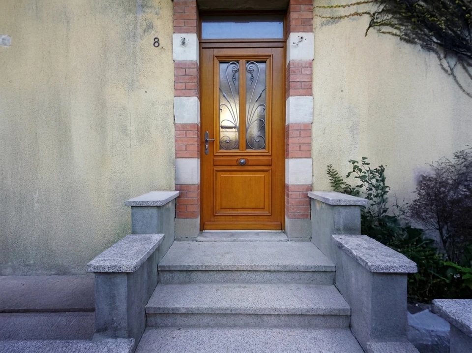 Photograph d'une fenêtre PVC à double vitrage ou d'un volet roulant en aluminium fraîchement installé sur la façade d'une maison rénovée, montrant le détail de la pose professionnelle et l'intégration harmonieuse avec la façade. La photo doit être prise de jour avec une bonne luminosité, montrant à la fois l'installation terminée et la qualité de finition. Image sans personne visible, focalisée uniquement sur le produit et la qualité de la pose.