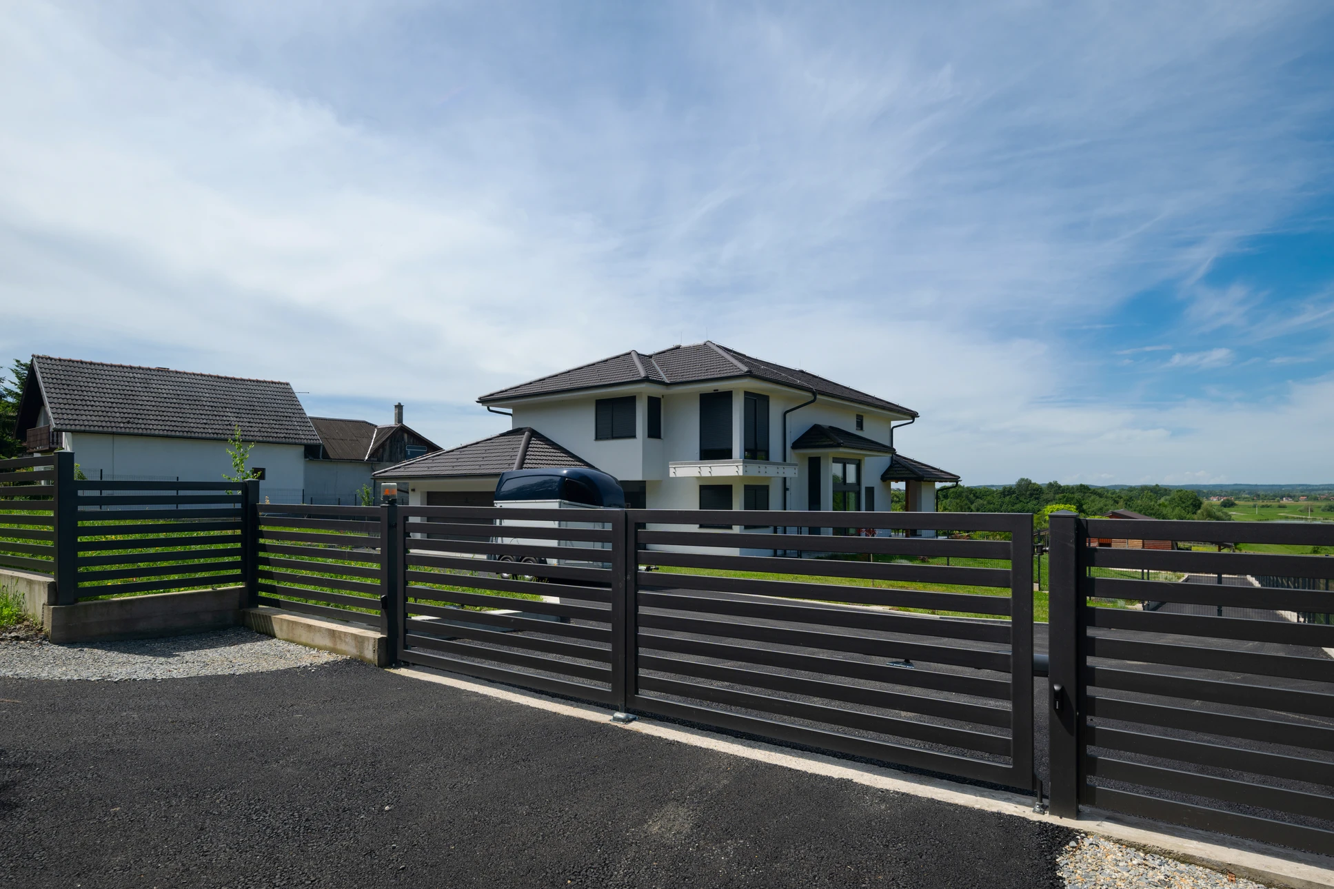 Extérieur résidentiel avec clôture moderne en panneaux métalliques anthracite à lames horizontales ajourées