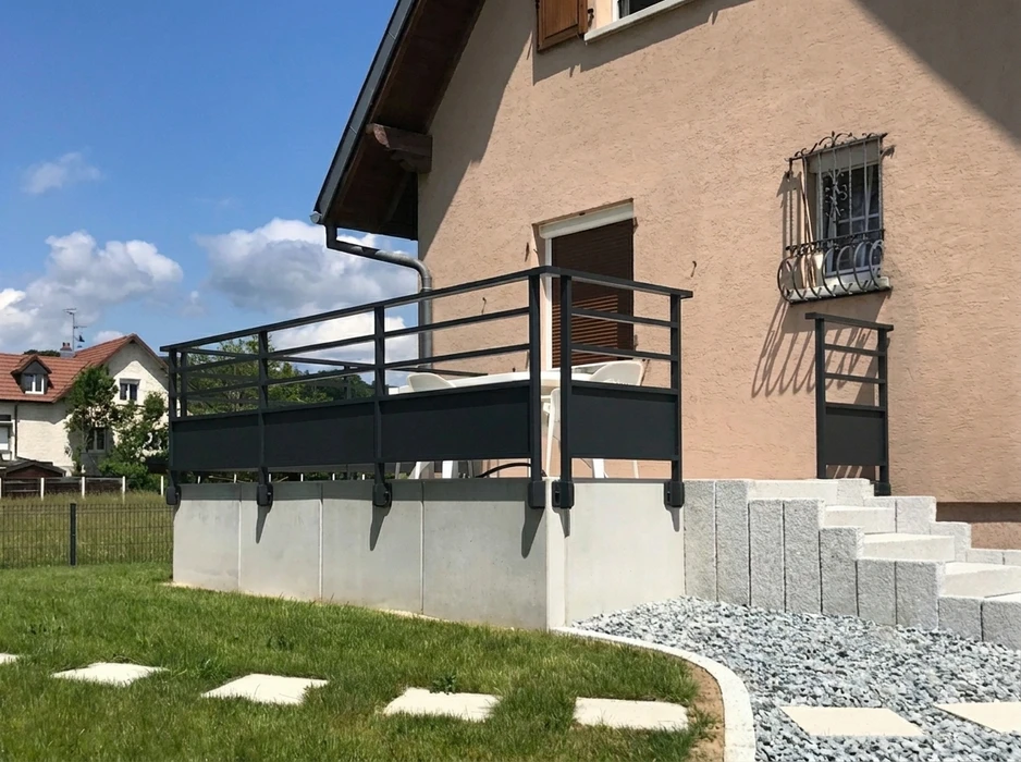 Escalier extérieur moderne avec rampe métallique noire menant à une véranda vitrée