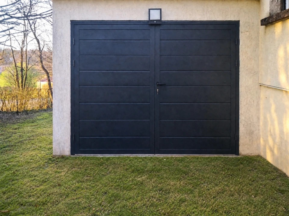 Un ouvrier installe une porte-fenêtre coulissante à châssis anthracite dans une maison en rénovation